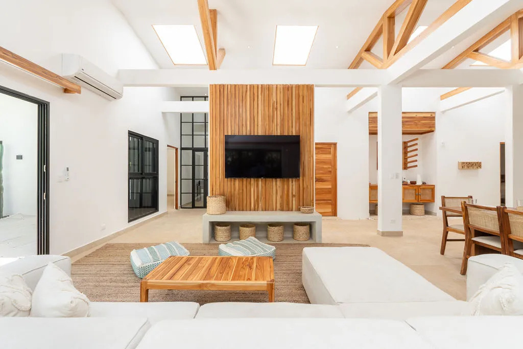 Open-plan living room at Casa Acqua with a vaulted beamed ceiling, slatted wood feature wall and glass doors to the garden