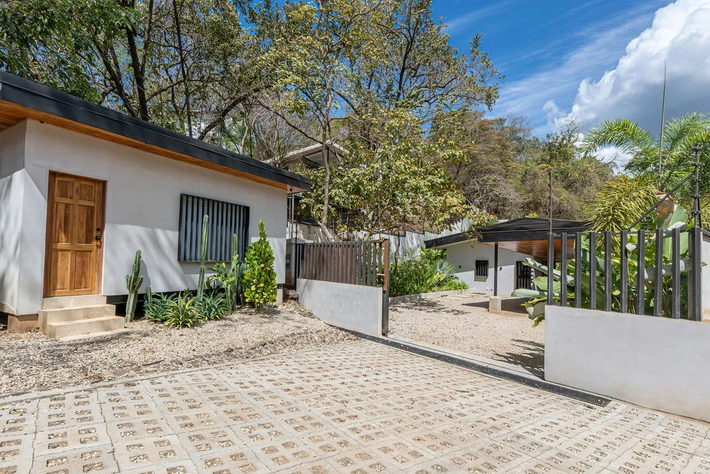 White exterior of the house with a patterned tile path leading to the entrance gate