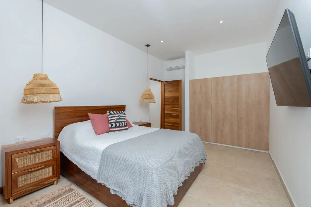 Bedroom with twin woven pendants, a wood-panelled wall and built-in wardrobe
