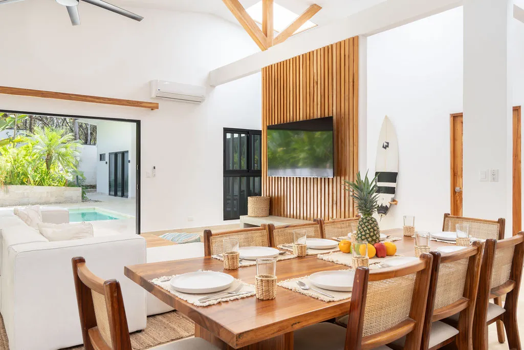 Dining table laid for a meal beneath the vaulted ceiling, with the pool visible beyond